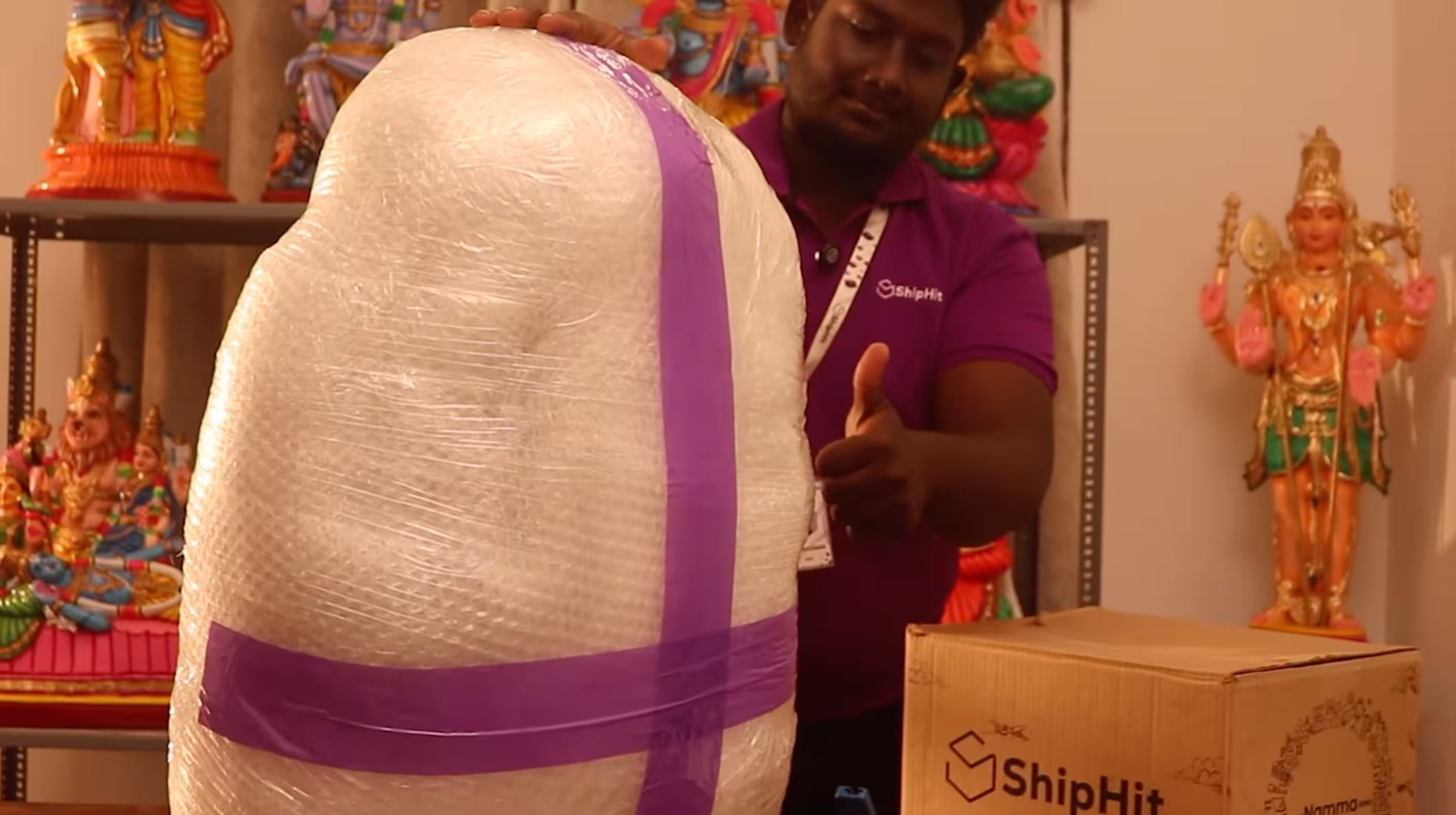 Extra bubble wrapping on a Golu doll secured with tape in a cross pattern beside a ShipHit carton